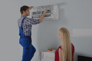 technition servicing ac with customer watching