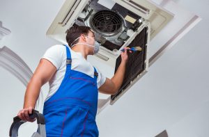 man blue overalls repairing AC