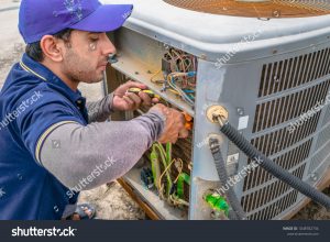 tech repairing AC unit